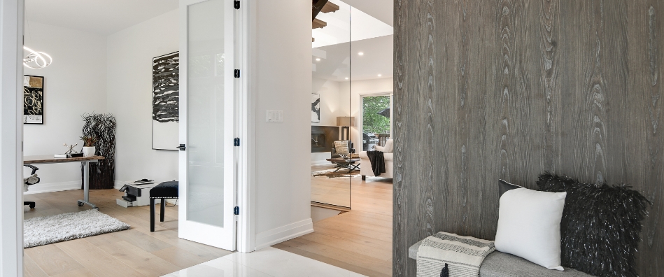 Modern interior with a cozy, open layout. Glass doors reveal an office with sleek furniture, while a soft bench with cushions adds warmth and style.